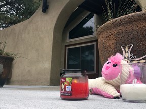 A small memorial of a stuffed animal and candles left by neighbors sits outside an Albuquerque, N.M, home on Tuesday, Dec. 6, 2016, a day after police say a man broke in and fatally shot three children. Albuquerque police say the three children were killed and their mother is in critical condition after the gunman shot them when they arrived home Monday night. Authorities say the gunman was in a short relationship with the mother. (AP Photo/Russell Contreras)