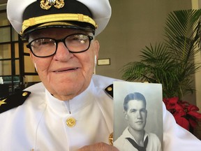 In this Monday, Dec. 5, 2016 photo, Jim Downing, 103, poses in a Navy uniform in Honolulu, with a photo of himself taken when he was about 20 years old. Downing is among a few dozen survivors of the Japanese attack on Pearl Harbor who plan to gather at the Hawaii naval base Wednesday, Dec. 7, 2016, to remember those killed 75 years ago. (AP Photo/Audrey McAvoy)