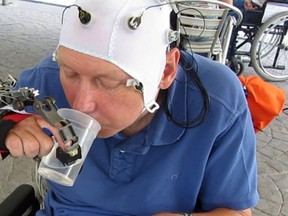 In this undated grab taken from video, a patient uses a robotic hand to drink from a cup, in Badalona, Spain. Scientists have developed a mind-controlled robotic hand that allows people with certain types of spinal injuries to perform everyday tasks such as using a fork or drinking from a cup. (Mario Cortese video via AP)