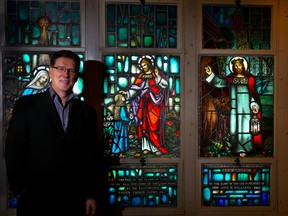 Tim Miller/The Intelligencer
Rev. David McMaster stands beside a row of stained glass windows at Eastminster United Church on Wednesday in Belleville. McMaster is the new minister for the east-end Belleville church.