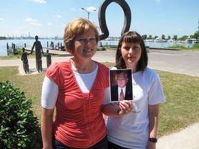 Sisters Leah Nielsen, left, and Stacy Cattran, shown in this file photo taken at the Victims of Chemical Valley Memorial in Centennial Park in Sarnia in 2011, hold a photograph of their father Bill Coulbeck, who died in 2008 of mesothelioma caused by exposure to asbestos. Cattran has joined a large number of individuals and groups urging Prime Minister Justin Trudeau to ban the use of asbestos in Canada.
(File photo/Sarnia Observer/Postmedia Network)