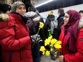 Nakita Valerio (right) with the Alberta Muslim Public Affairs Council, hands out flowers to women wearing hijabs at the University of Alberta LRT station, on Wednesday Dec. 7, 2016. The Edmonton police hate crimes unit has a suspect in custody following a Nov. 8 incident where a man threatened two Muslim women with a noose at the LRT station. DAVID BLOOM/Postmedia