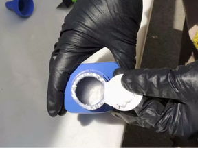 In this June 27, 2016 photo provided by the Royal Canadian Mounted Police, a member of the RCMP opens a printer ink bottle containing the opioid carfentanil imported from China, in Vancouver. Drug dealers have been cutting carfentanil and its weaker cousin, fentanyl, into heroin and other illicit drugs to boost profit margins.