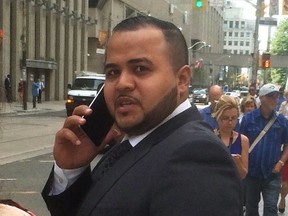 Moazzam Tariq talks on his cellphone outside a Toronto courthouse in August 2016. (SAM PAZZANO, Toronto Sun)