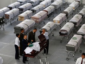 Funeral employees cover a casket, decorated with a Chapecoense soccer team logo, containing the remains of a team member at San Vicente funeral home in Medellin, Colombia, Friday, Dec. 2, 2016. (AP Photo/Fernando Vergara)