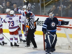 Michael Hutchinson looks up at the replay as the Rangers celebrate their first-period goal. (JOHN WOODS/Canadian Press)