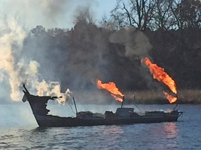 This image provided by Mike Ostrander shows the burning hulk of a boat on the James River in Richmond, Va. Friday Dec. 9, 2016. The boat is one of several that burned during a fire at the Richmond Boat Basin. (Mike Ostrander via AP)