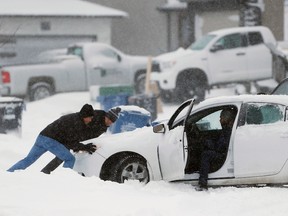 People push a stuck car after two days of snow in Winnipeg earlier this week. (THE CANADIAN PRESS/John Woods)