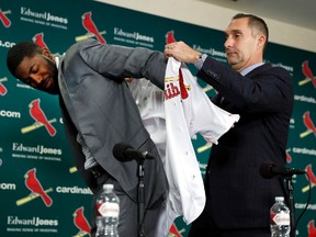 St. Louis Cardinals general manager John Mozeliak puts a Cardinals jersey on Dexter Fowler during a baseball news conference announcing the signing of the free agent center fielder on Dec. 9, 2016, in St. Louis. (AP Photo/Jeff Roberson)