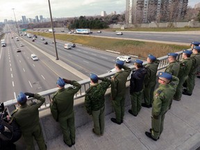 A group of Canadian Forces pilots in training at Seneca College stand on the on the Don Mills bridge over Hwy. 401 and  salute the passing of motorcade of Canadian Forces CF18 pilot Capt. Thomas McQueen who was killed last week. (Michael Peake/Toronto Sun)