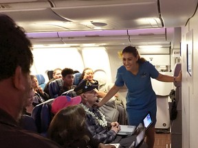 In a Thursday, Nov. 8, 2016 photo provided by Brooks Onishi, Hawaiian Airlines flight attendant Lehua Beltrame-Tevaga greets passenger Ray Richmond during a flight from Honolulu to San Diego. (AP Photo/Brooks Onishi)