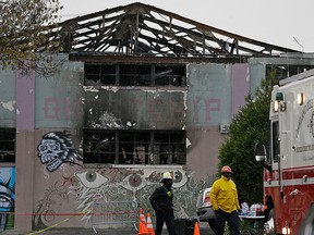 This Wednesday, Dec. 7, 2016 file photo shows Oakland fire officials walk past the remains of the Ghost Ship warehouse damaged from a deadly fire in Oakland, Calif.  (AP Photo/Eric Risberg, File)