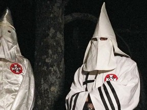 In this Friday, Dec. 2, 2016 photo, two masked Ku Klux Klansmen stand on a muddy dirt road during an interview near Pelham, N.C. (AP Photo/Jay Reeves)