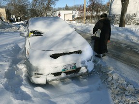 A pedestrian walks past a vehicle ticketed as part of the residential parking ban for snow clearing, on Guelph Street north of Corydon Avenue, in Winnipeg on Sat., Dec. 11, 2016. (Kevin King/Winnipeg Sun/Postmedia Network)