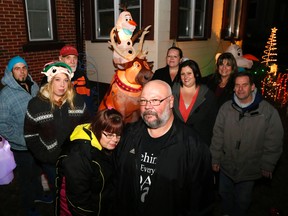 Margie and Fred Rushlow stand before the Christmas display honouring the memory of their son, Aaron, after donors on Saturday replaced stolen decorations with new ones (far left and centre). Among the donors were, from left, Adam Pack, Amanda Jarvis (who organized the donations), Stan Jarvis, Kim McKenzie, Katy Winter, Angeli Scotti and Nick Thomas.