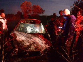 Volunteers look inside a car involved in an oil tanker explosion in Karai, Naivasha, on December 11, 2016. At least 25 people have been killed and several others injured when a fuel tanker lost control and rammed into several vehicles before bursting into flames in Naivasha. (SIMON MAINA/AFP/Getty Images)