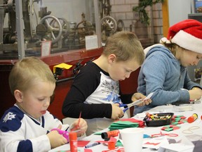 Youngsters work diligently to create Christmas decorations during the open house at the Oil Museum of Canada on Saturday. From left were St. Pierre siblings: Xavier, 4, Wesley, 7, and Caroline 9. (Neil Bowen/Sarnia Observer)