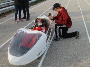 A Northern Eco Team member sets his stopwatch in order to time the single-passenger car as it drives along Northern Collegiate's 400-metre track, driven by team member Maria Peregoudov. (Carl Hnatyshyn/Postmedia Network)