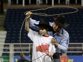Levi Simpson, shown here demonstrating roping to a young visitor at the Rodeo Magic event at the Canadian Finals Rodeo at Rexall Place in November, was named world champion with team roping partner Jeremy Buhler Sunday at the National Finals Rodeo in Las Vegas, Nev. (Larry Wong)