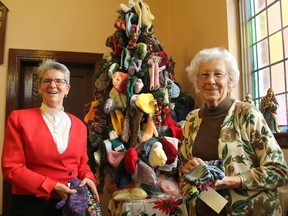 Rev. Susan McAllister, left, minister of Princess Street United Church, and Jean Reid stand next to the Christmas tree covered in handmade tuques, mitts and scarves that congregation members have made to be donated to needy families. (Michael Lea/The Whig-Standard)