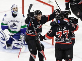 Vancouver Canucks goalie Ryan Miller looks on at left as Carolina Hurricanes' Joakim Nordstrom, of Sweden, and Elias Lindholm, of Sweden, congratulate Justin Faulk (27) following Faulk's goal during third period of an NHL hockey game in Raleigh, N.C., Tuesday, Dec. 13, 2016. Carolina won 8-6. (AP Photo/Gerry Broome)