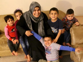 Kusay Ahmed, 7 tries to hide from a photographer at his families home in south London on Tuesday December 13, 2016. Kusay is dragged into the photo by his mom Fatima Hacali, also in the shots are sisters Esra and Sedra Ahmed and brothers Luay and Abdullah Ahmed. Mike Hensen/The London Free Press/Postmedia Network