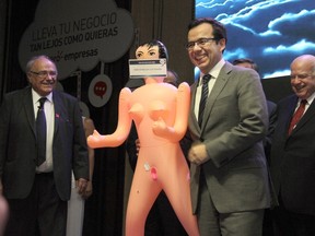 Chile's Economy Minister, Luis Felipe Cespedes, receives an inflatable doll from the president of the Association of Exporters and Manufactures (Asexma) Roberto Fantuzzi during a Chistmas dinner of the export union in Santiago on Dec. 13, 2016. (AFP PHOTO/George CADENASGEORGE)