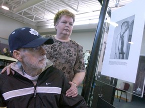 The late Blayne Kinart and his wife Sandy Kinart are shown in this file photo looking at photos of Blayne included in a photo documentary titled Workers: Life and Loss, on display at the OHCOW Clinic in Sarnia. Blayne died of mesothelioma, a rare cancer caused by exposure to asbestos. Sandy, a member of the Sarnia group Victims of Chemical Valley, was among those in Sarnia welcoming news Thursday that Canada plans to ban use of asbestos by 2018. (File photo)