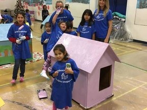 Jasmine Colucci, a community nurse and dog rescue volunteer, helps children in Bloodvein First Nation paint the dog houses they constructed over two days in the gymnasium of Miskoseepi School. (HANDOUT PHOTO)