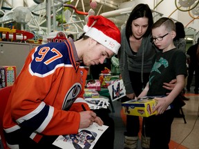 Edmonton Oilers captain Connor McDavid autographs a photo for Stollery Children’s Hospital patient Luca Flynn, 8, and his mother Jennifer. McDavid and other members of the team made their annual visit to the hospital on December 15, 2016. LARRY WONG / POSTMEDIA