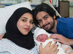 A handout picture released on December 15, 2016 shows Moaza Al Matrooshi (L) posing with her husband Ahmed and newly born son at a hospital in London on December 14, 2016. Moaza Al Matrooshi has become the first to give birth after having her fertility restored using ovarian tissue frozen before the onset of puberty, doctors said yesterday. Al Matrooshi, 24, had her right ovary removed when she was nine years old before undergoing chemotherapy treatment for a severe blood disorder, according to the University of Leeds where the ovarian tissue was frozen. (AFP PHOTO / Joe MILES)