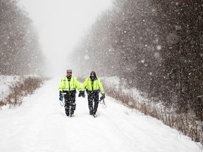 Members of Ottawa Police's Emergency Services Unit walk down the train line that crosses McCarthylooking for evidence from the double homicide.