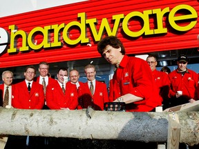 During the grand opening of Home Hardware store, owner Jerry Dolynchuk, centre, uses a chain saw to cut a log while Home Hardware president, Walter Hachborn, right, watches in this Nov. 17, 2005 file photo. (EDMONTON JOURNAL/Greg Southam)