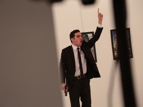 An unnamed gunman gestures after shooting the Russian Ambassador to Turkey, Andrei Karlov, at a photo gallery in Ankara, Turkey, Monday, Dec. 19, 2016. (AP Photo/Burhan Ozbilici)