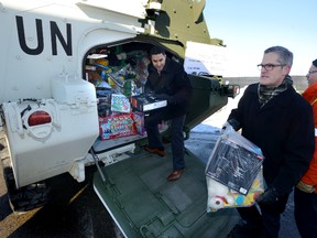 Paul Cardoso, left, and Doug Wilson-Hodge, of General Dynamics Land Systems-Canada Corporate Affairs, help Ken Wedemire unload an LAV full of toys to donate to the annual Toys for Tots campaign on Monday. In addition GDLS made a donation of $22,000 to the campaign. (MORRIS LAMONT, The London Free Press)