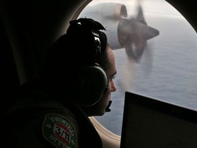 In this March 22, 2014 file photo, flight officer Rayan Gharazeddine scans the water in the southern Indian Ocean off Australia from a Royal Australian Air Force AP-3C Orion during a search for the missing Malaysia Airlines Flight MH370. A team of international investigators hunting for missing Malaysia Airlines Flight 370 said Tuesday, Dec. 20, 2016 it has concluded the plane is unlikely to be found in a stretch of the Indian Ocean search crews have been combing for two years, and may instead have crashed in an area farther to the north. (AP Photo/Rob Griffith, File)