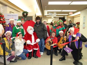 Santa and Mrs. Claus had a lot of help from the community last week to greet many local children at the Ontario Northland Station. The Santa Train brought Santa, his wife and four elves to greet the children. Each child had a chance to sit on Santa's knee and receive a bag of goodies. Santa poses with members of the Lions Club and local musicians who assisted him on his trip to  town.