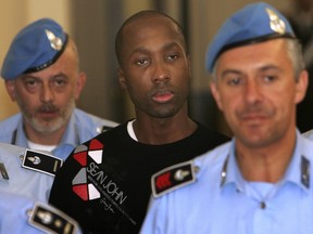 This Friday, Sept. 26, 2008 file photo shows Rudy Hermann Guede from the Ivory coast, centre, escorted by Italian penitentiary police officers as he leaves Perugia's court after a hearing, central Italy. Lawyers for the Ivorian man convicted in the 2007 slaying of Meredith Kercher are petitioning a Florence appeals court Tuesday, Dec. 20, 2016 to overturn the only conviction in the case, arguing the acquittals of the high-profile defendants Raffaele Sollecito and Amanda Knox are in conflict with the guilty verdict against Rudy Hermann Guede. (AP Photo/Pier Paolo Cito)