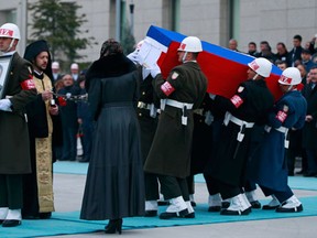 Members of a Turkish forces honour guard carry the Russian flag-draped coffin of Russian Ambassador to Turkey Andrei Karlov who was assassinated Monday, as an officer, left, holds his picture during a ceremony at the airport in Ankara, Turkey, (AP Photo/Emrah Gurel)