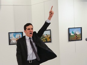 In this Monday, Dec. 19, 2016 file photo, Mevlut Mert Altintas shouts after shooting Andrei Karlov, right, the Russian ambassador to Turkey, at an art gallery in Ankara, Turkey. At first, AP photographer Burhan Ozbilici thought it was a theatrical stunt when a man in a dark suit and tie pulled out a gun during the photography exhibition. The man then opened fire, killing Karlov. (AP photo/Burhan Ozbilici)