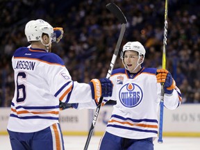 Tyler Pitlick celebrates his goal against the Blues Monday with Oilers defenceman Adam Larsson. Pitlick was sent back to Edmonton to be examined by doctors following a mishap that saw him leave Monday's game with a possible leg injury. (AP Photo)