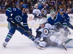Vancouver Canucks defenceman Ben Hutton (27) watches as Winnipeg Jets right wing Patrik Laine (29) slides into Canucks goaltender Jacob Markstrom during first period NHL action in Vancouver, B.C. Tuesday, Dec. 20, 2016. THE CANADIAN PRESS/Jonathan Hayward