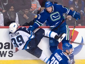 Vancouver Canucks defenceman Alex Biega (55) goes into the boards with Winnipeg Jets defenceman Toby Enstrom (39) during third period NHL action in Vancouver, B.C. Tuesday, Dec. 20, 2016. THE CANADIAN PRESS/Jonathan Hayward