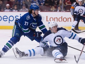 Vancouver Canucks defenceman Ben Hutton (27) fights for control of the puck with Winnipeg Jets right winger Patrik Laine during Tuesday night's game. (THE CANADIAN PRESS/Jonathan Hayward)