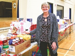 Betty Whitney, chairman of the Vulcan Regional Food Bank Society stands beside the long row of food and household items donated to the food bank by the staff and students from County Central High School Wednesday morning.