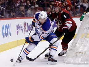 Connor McDavid cuts past Coyotes defenceman Connor Murphy during Wednesday's game in Glendale, Ariz. Coyotes forward Max Domi is out with an injury sustained to his hand during a fight, a situation McDavid went through in his final year of junior hockey. (AP Photo)