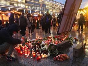 A visitor lays a candle at a makeshift memorial inside the reopened Breitscheidplatz Christmas market only a short distance from where three days ago a truck plowed into the market, killed 12 people and injured dozens in a terrorist attack on December 22, 2016 in Berlin, Germany. The Breidscheidplatz Christmas market is reopening today, though its small amusement rides and bright lights displays will remain shut off in a sign of continuing mourning for the attack victims. Meanwhile police have launched a European-wide manhunt for Anis Amri, a 24-year-old Tunisian man they suspect of having driven the truck. (Photo by Sean Gallup/Getty Images)