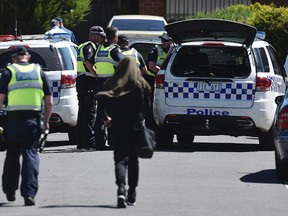 Police accompany a woman as they attend the scene where a house was raided at Meadow Heights in Melbourne, Australia, Friday, Dec. 23, 2016. (Julian Smith/AAP Image via AP)