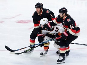 Ducks’ Ondrej Kase gets pushed around by Sens’ Marc Methot (left) and Erik Karlsson on Thursday night. (THE CANADIAN PRESS)