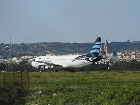 An Afriqiyah Airways plane from Libya stands on the tarmac at Malta's Luqa International airport, Friday, Dec. 23, 2016. Malta's state television says two hijackers who diverted a Libyan commercial plane to the Mediterranean island nation have threatened to blow it up. (AP Photo/Jonathan Borg)